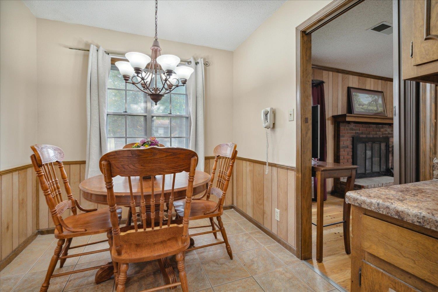 4839 Yale Road Memphis, TN 38128 - Photo 12 of 27 Tiled dining space with wooden walls, a textured ceiling, a notable chandelier, and a fireplace