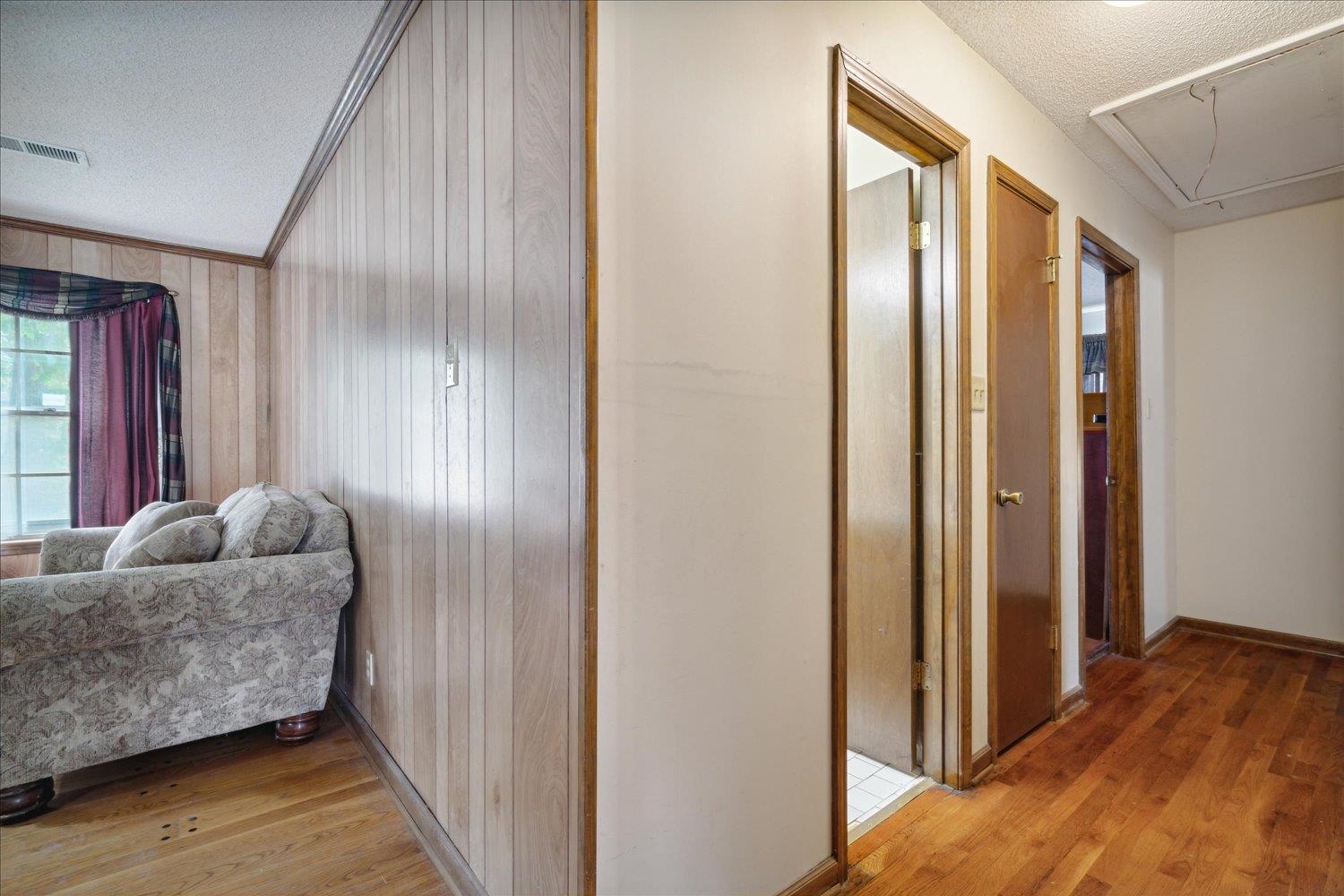 4839 Yale Road Memphis, TN 38128 - Photo 20 of 27 Hallway with wooden walls, wood-type flooring, ornamental molding, and a textured ceiling