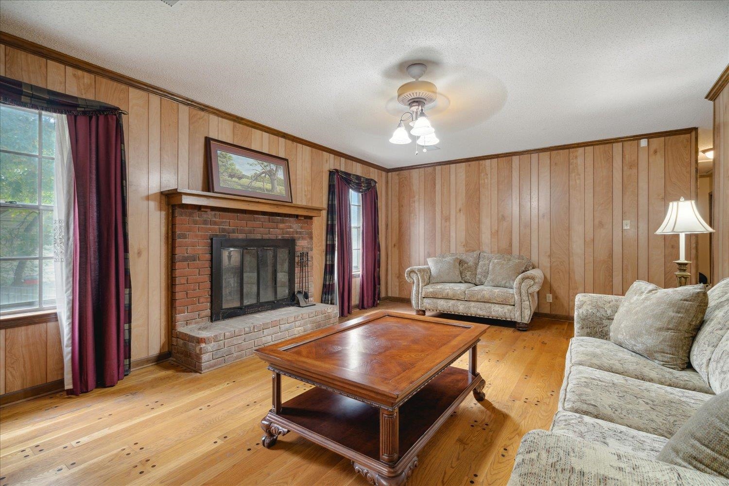 4839 Yale Road Memphis, TN 38128 - Photo 9 of 27 Living room with ornamental molding, a textured ceiling, wood walls, light hardwood / wood-style floors, and a brick fireplace
