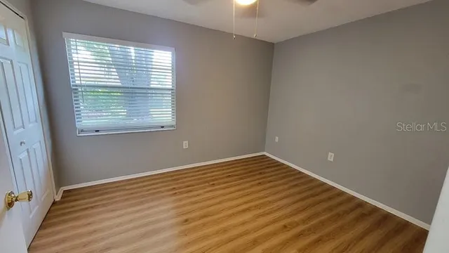 a view of an empty room with wooden floor and a window