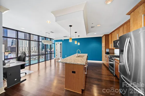 a kitchen with stainless steel appliances granite countertop a refrigerator a stove and a wooden floors