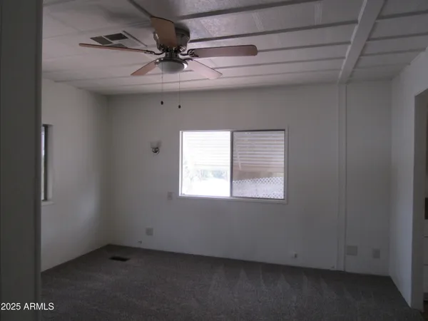 an empty room with a ceiling fan and window