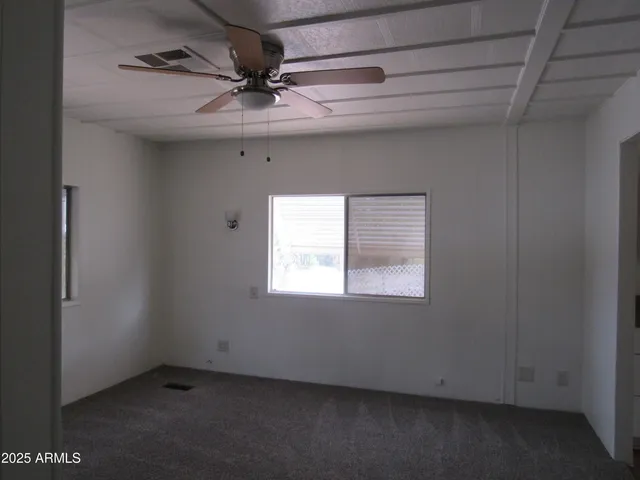 an empty room with a ceiling fan and window