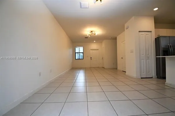 an empty room with kitchen view and windows