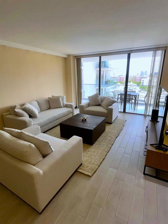 19707 Turnberry Way, Unit 8L Miami, FL 33180 - Photo 17 of 39 a living room with furniture and a floor to ceiling window