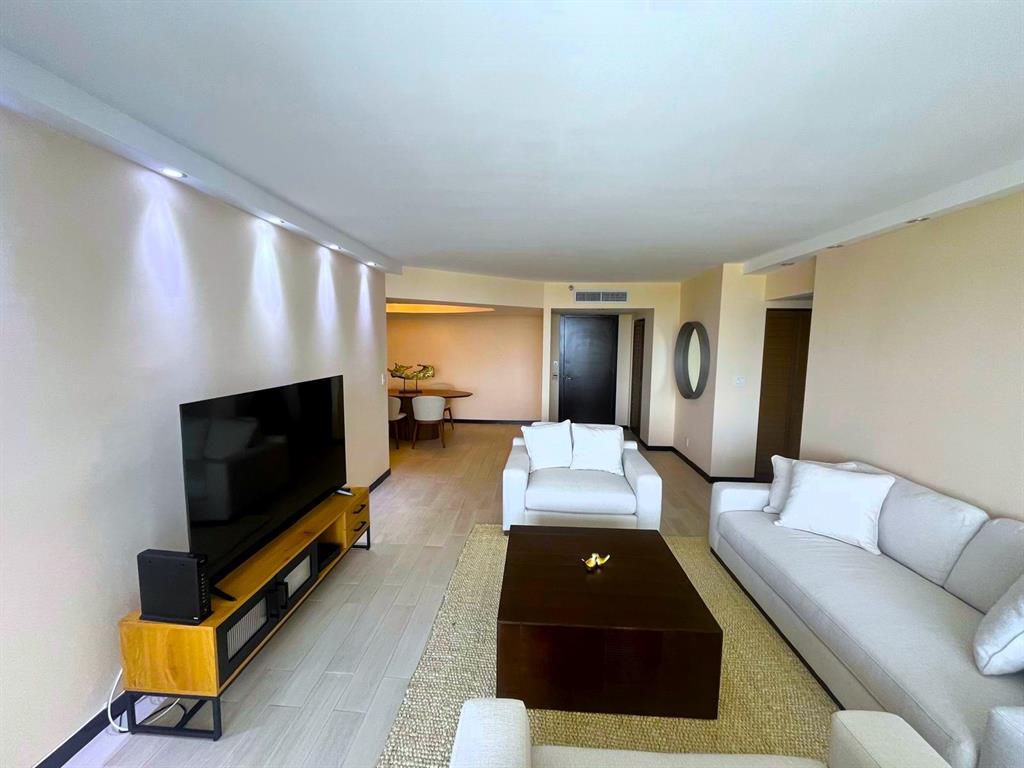 19707 Turnberry Way, Unit 8L Miami, FL 33180 - Photo 2 of 39 a living room with furniture and a flat screen tv