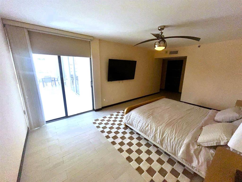 19707 Turnberry Way, Unit 8L Miami, FL 33180 - Photo 8 of 39 a bedroom with a bed and a flat screen tv