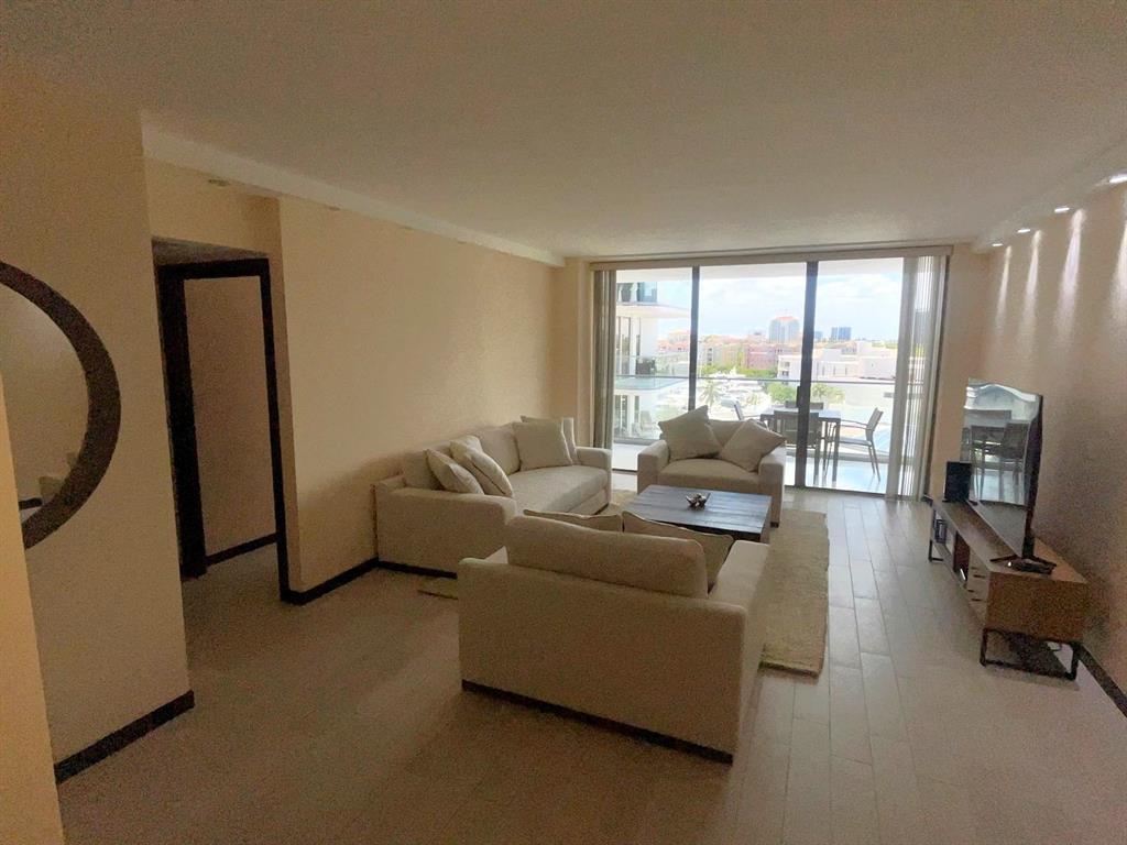 19707 Turnberry Way, Unit 8L Miami, FL 33180 - Photo 9 of 39 a living room with furniture and a flat screen tv