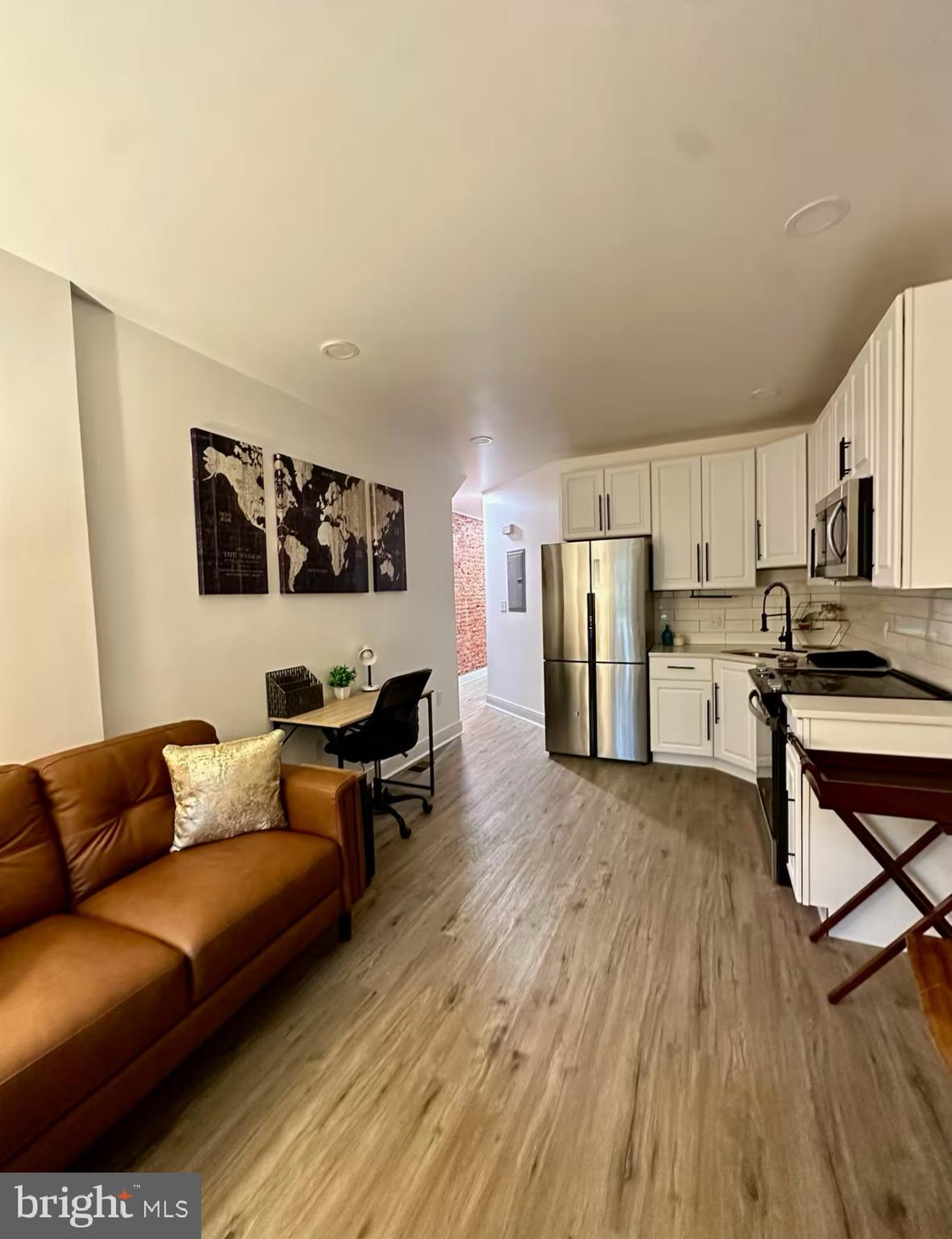 a living room with stainless steel appliances furniture and a wooden floor