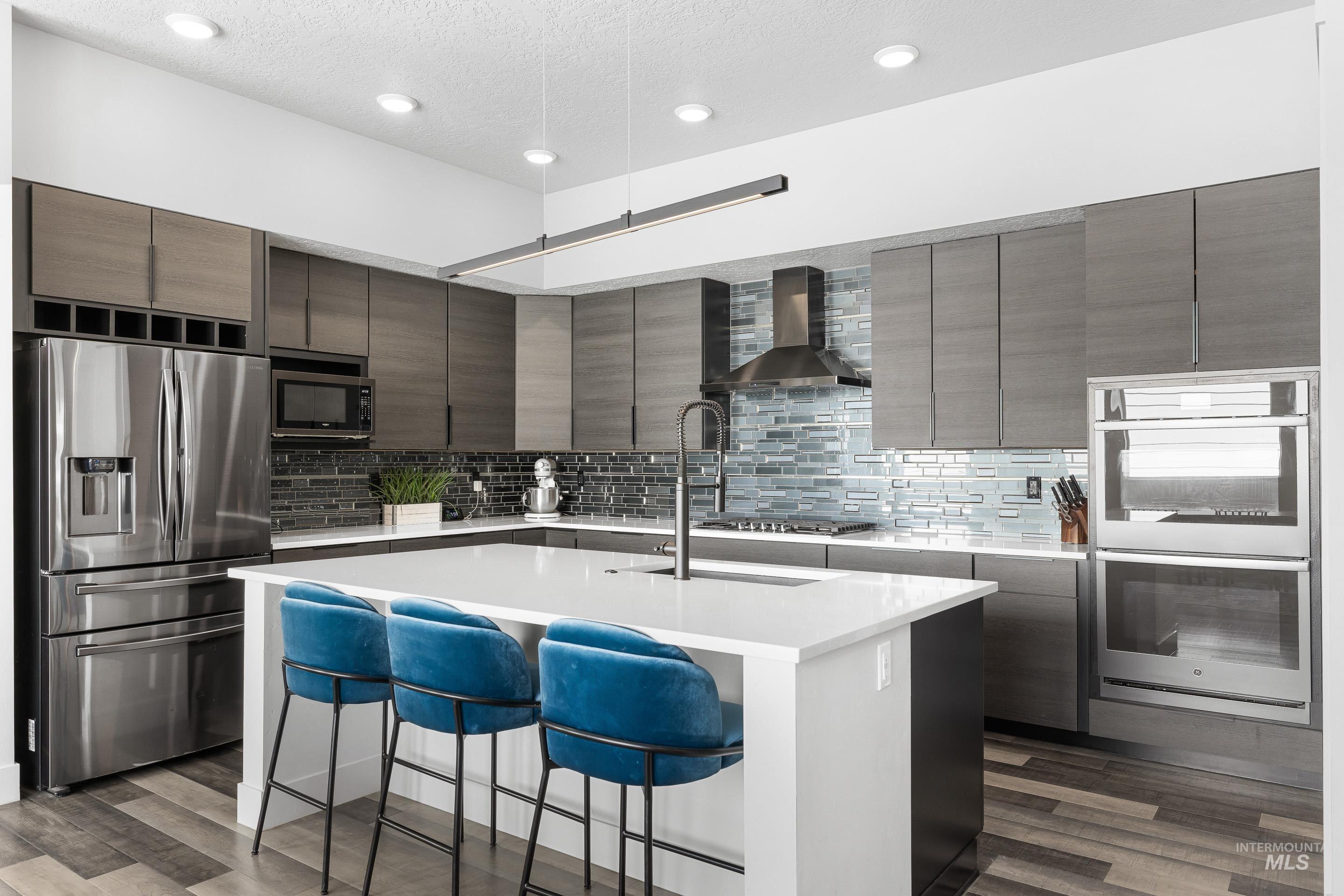 3483 South Grenze Way Meridian, ID 83642 - Photo 6 of 30 Kitchen with stainless steel appliances, dark wood finish cabinets, a breakfast bar, an island with sink, and light stone counters