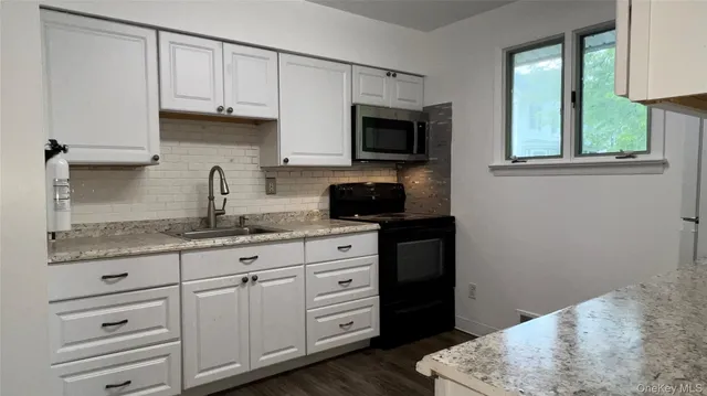 a kitchen with granite countertop a sink and a stove top oven