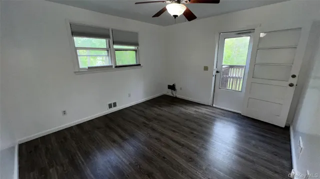 an empty room with wooden floor chandelier and windows