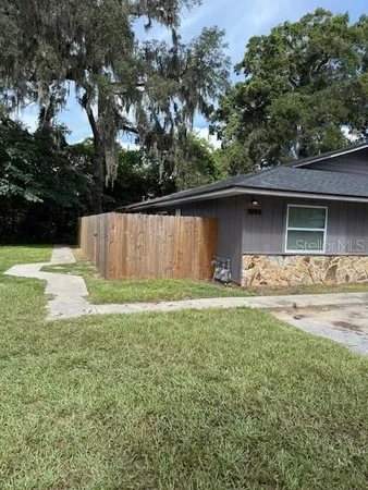 a front view of house with yard and trees in the background