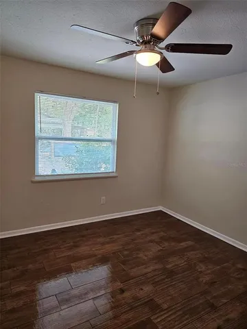 an empty room with wooden floor closet and fan