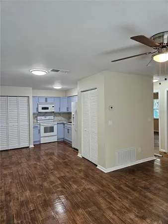 an empty room with wooden floor fan and windows