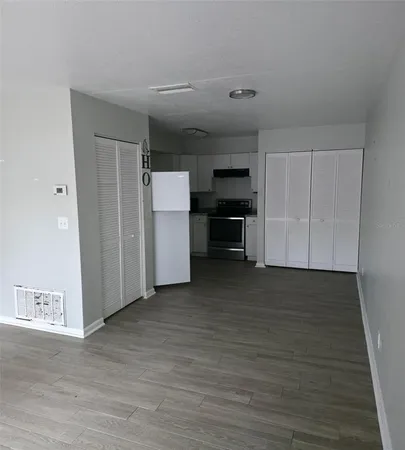 an empty room with wooden floor and fan