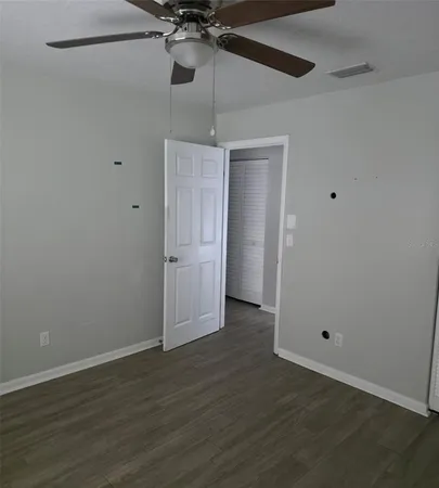 an empty room with a ceiling fan and wooden floor