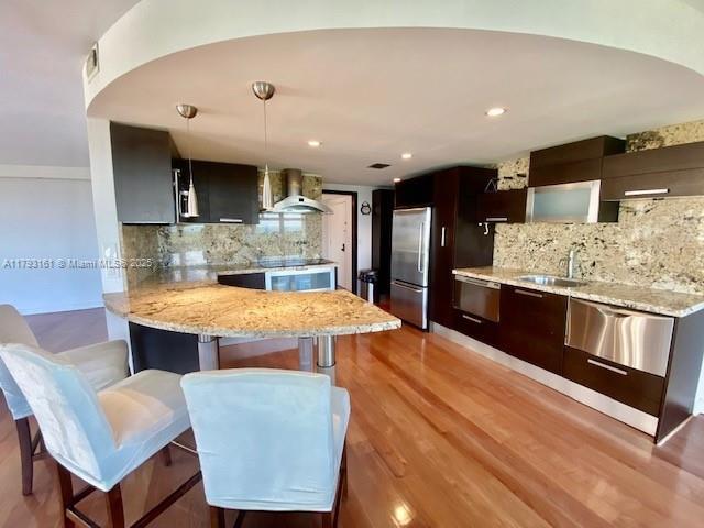 1121 Crandon Boulevard, Unit D802 Key Biscayne, FL 33149 - Photo 13 of 30 a kitchen with stainless steel appliances kitchen island granite countertop a table chairs in it and wooden floors