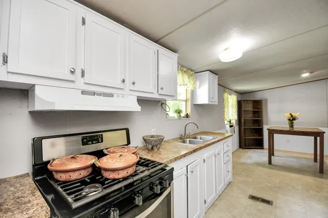 a kitchen with granite countertop white cabinets and window