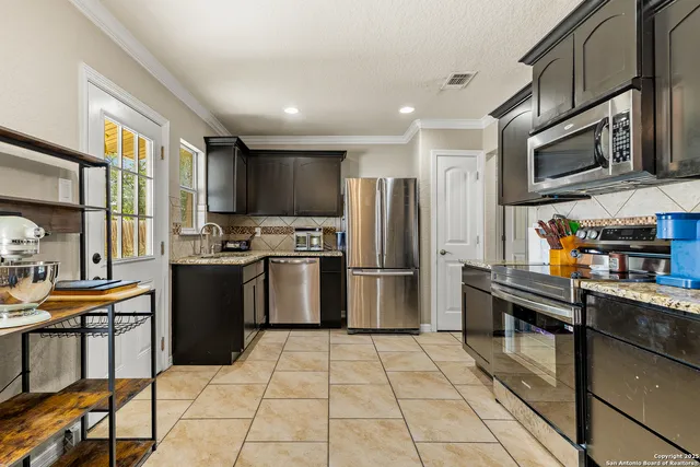 a kitchen with granite countertop a refrigerator and a stove top oven