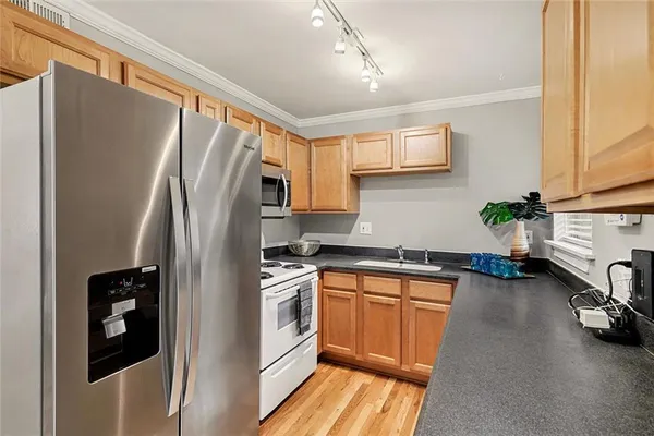 a kitchen with stainless steel appliances a refrigerator a sink a stove and a refrigerator with wooden floor
