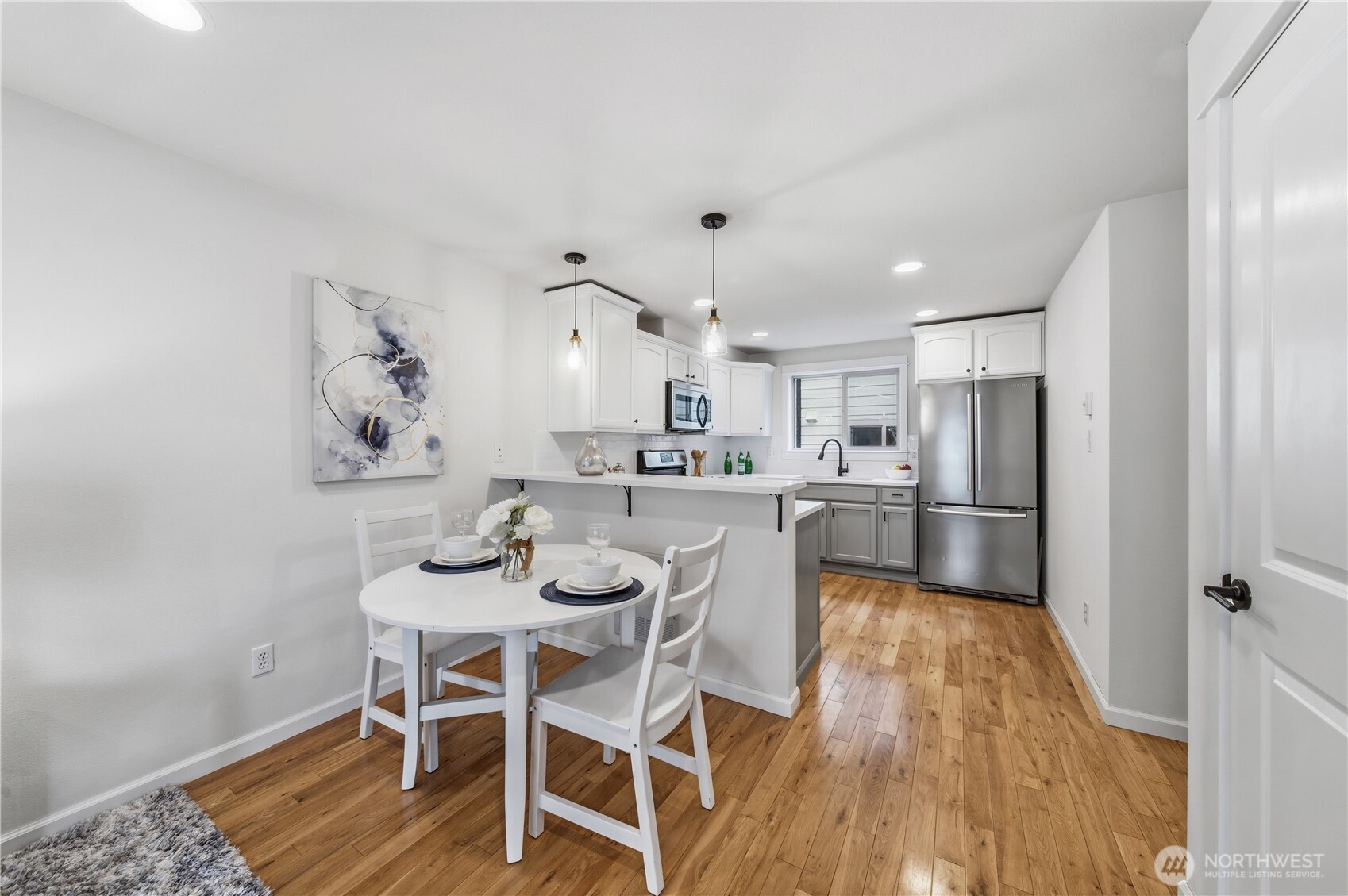 1122 North 92nd Street, Unit B Seattle, WA 98103 - Photo 5 of 28 a kitchen with a dining table chairs refrigerator and wooden floor