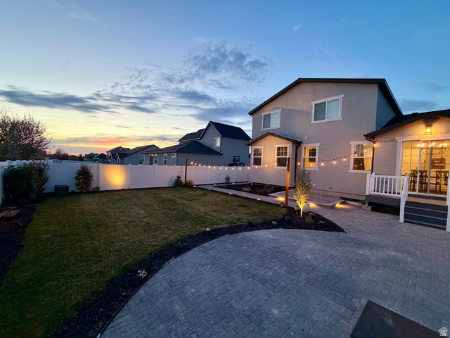 3359 Eurasian Crane Road Clinton, UT 84015 - Photo 66 of 71 Back of property at dusk featuring stucco siding, a patio, a fenced backyard, and a residential view