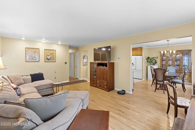 a living room with furniture and a dining table with wooden floor