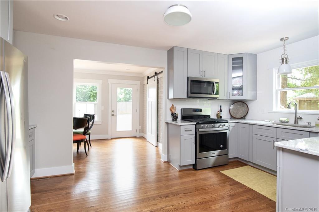 2431 Eaton Road Charlotte, NC 28205 - Photo 12 of 19 a kitchen with granite countertop a stove top oven a sink dishwasher a dining table and chairs with wooden floor