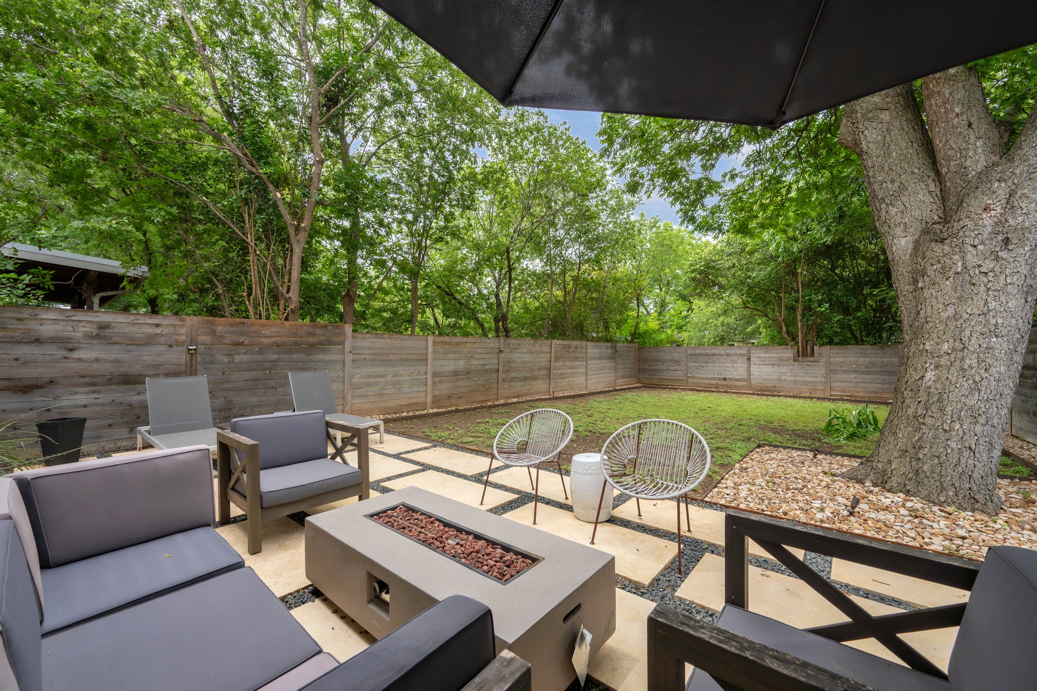 1409 Alegria Road, Unit A Austin, TX 78757 - Photo 21 of 24 A secluded outdoor living space features a fire pit, patio, and fenced yard, perfect for tranquil evenings.