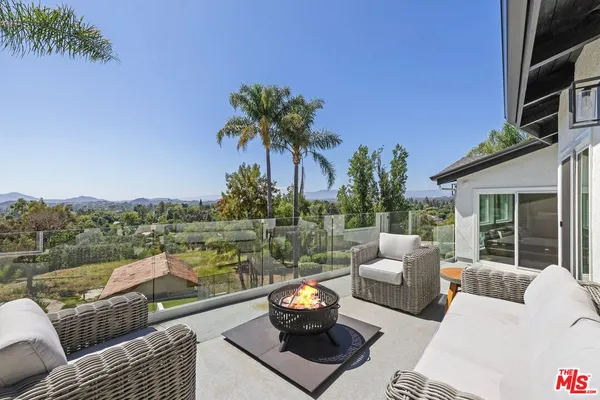 a view of a patio with couches potted plants and a palm tree