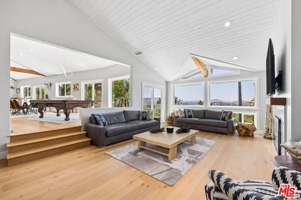 a living room with furniture kitchen view and a large window