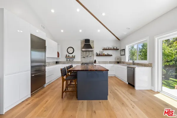 a kitchen with kitchen island granite countertop wooden floors stainless steel appliances a sink and a large window