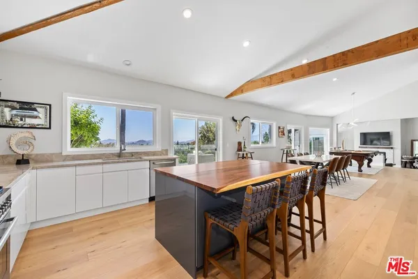 a kitchen with stainless steel appliances kitchen island granite countertop a table chairs sink and cabinets