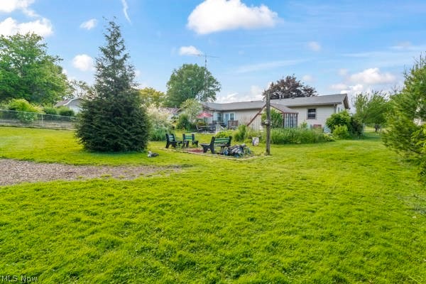 5030 Warren - Sharon Road Vienna, OH 44473 - Photo 17 of 50 Expansive green lawn with mature landscaping, a designated fire pit area, and a privacy fence bordering the property