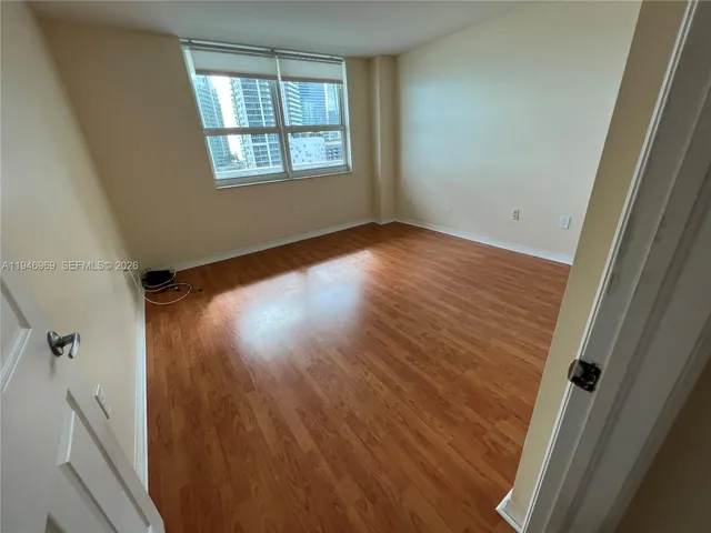 a view of empty room with wooden floor and fan