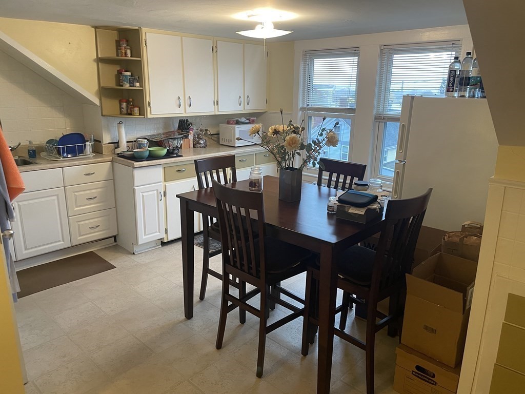 a kitchen with a dining table chairs and refrigerator