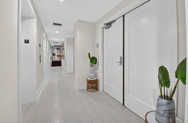 a view of a hallway with wooden floor and a chandelier