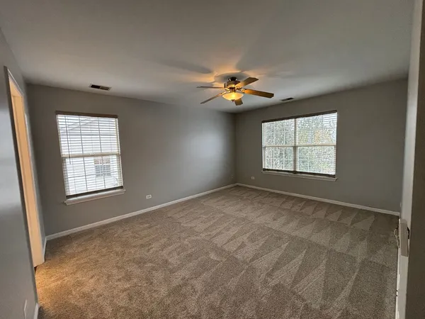 an empty room with windows and chandelier fan