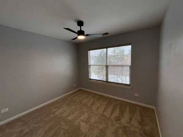 an empty room with a window and a ceiling fan