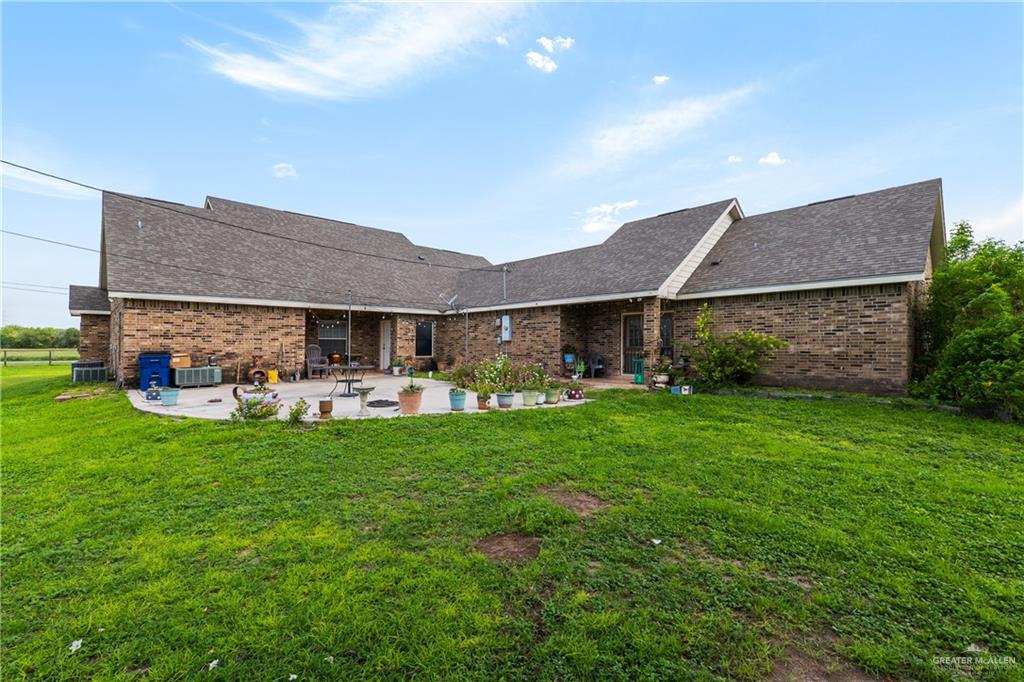 605 South Whalen Road Donna, TX 78537 - Photo 4 of 21 Expansive green lawn with a large, L-shaped brick exterior and a concrete patio