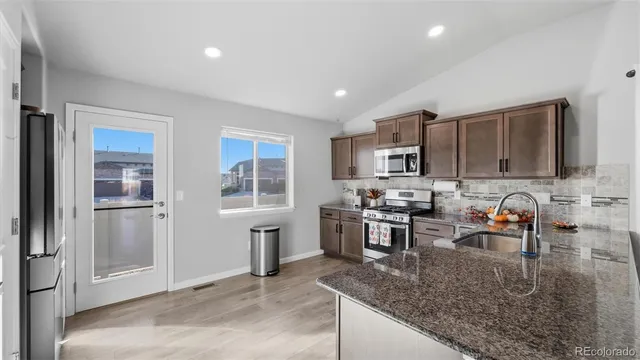 a kitchen with stainless steel appliances granite countertop a refrigerator stove microwave and sink