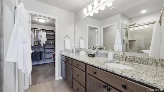 a bathroom with a granite countertop double vanity sink and a mirror
