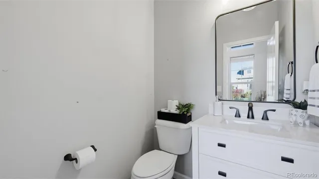 a bathroom with a toilet sink vanity and mirror