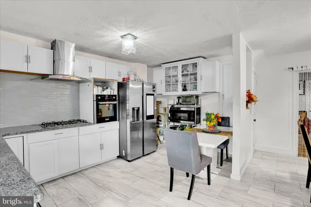 a kitchen with stainless steel appliances kitchen island granite countertop a refrigerator and a stove top oven