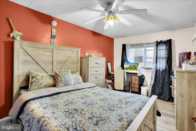 a bedroom with a bed a dresser and wooden floor