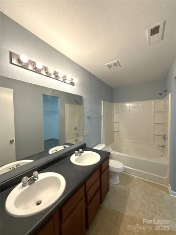 a bathroom with a double vanity sink a mirror and a bathtub