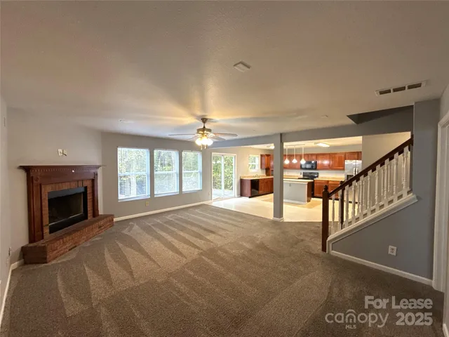 a view of an empty room with a fireplace and windows