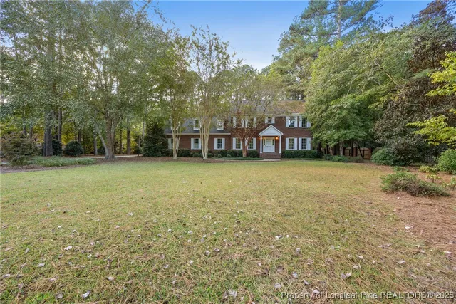 a view of a large pool with lawn chairs and large trees