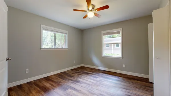 a view of empty room with wooden floor and fan